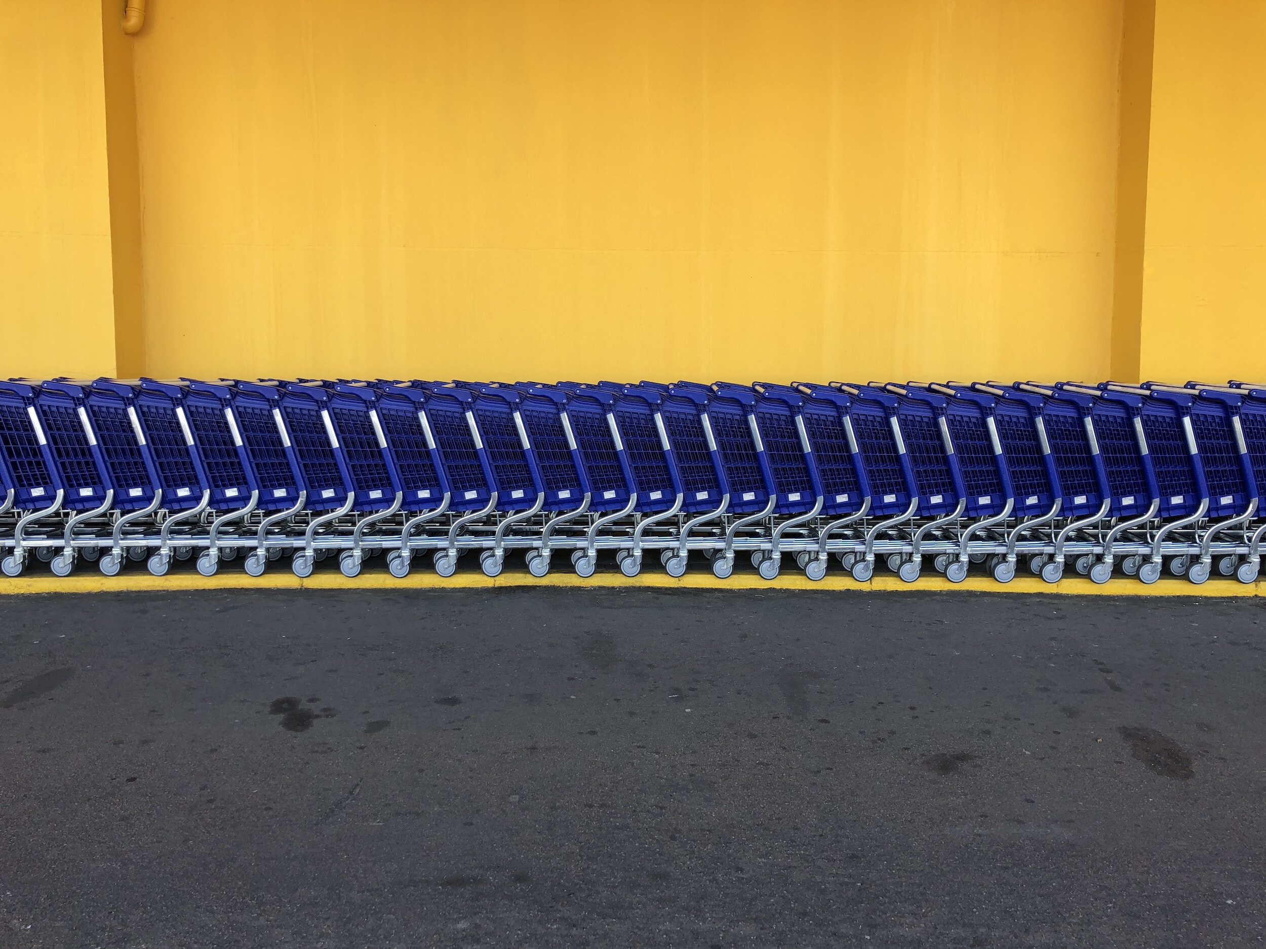 a yellow wall with Walmart shopping carts lined up in front of it.
