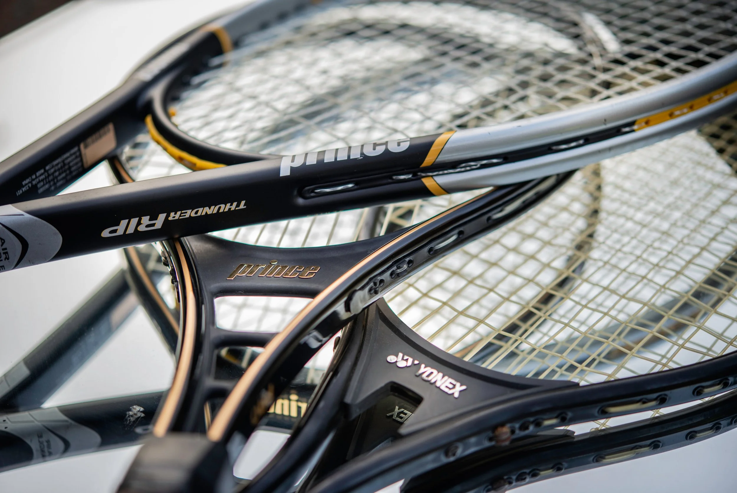 Five tennis rackets lying on top of one another.