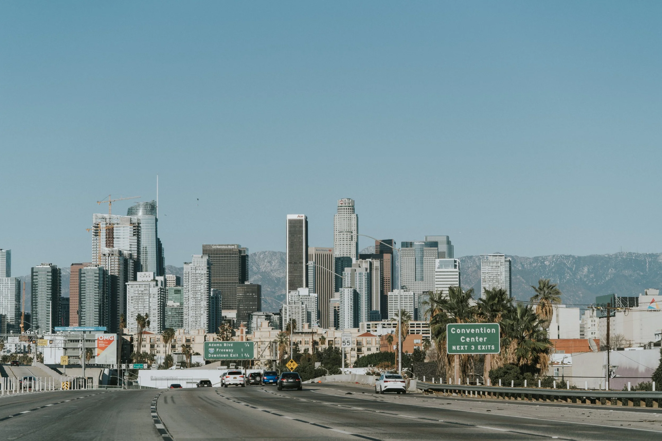Skyline of city against a blue sky. Freeway sign shows "Convention Center.