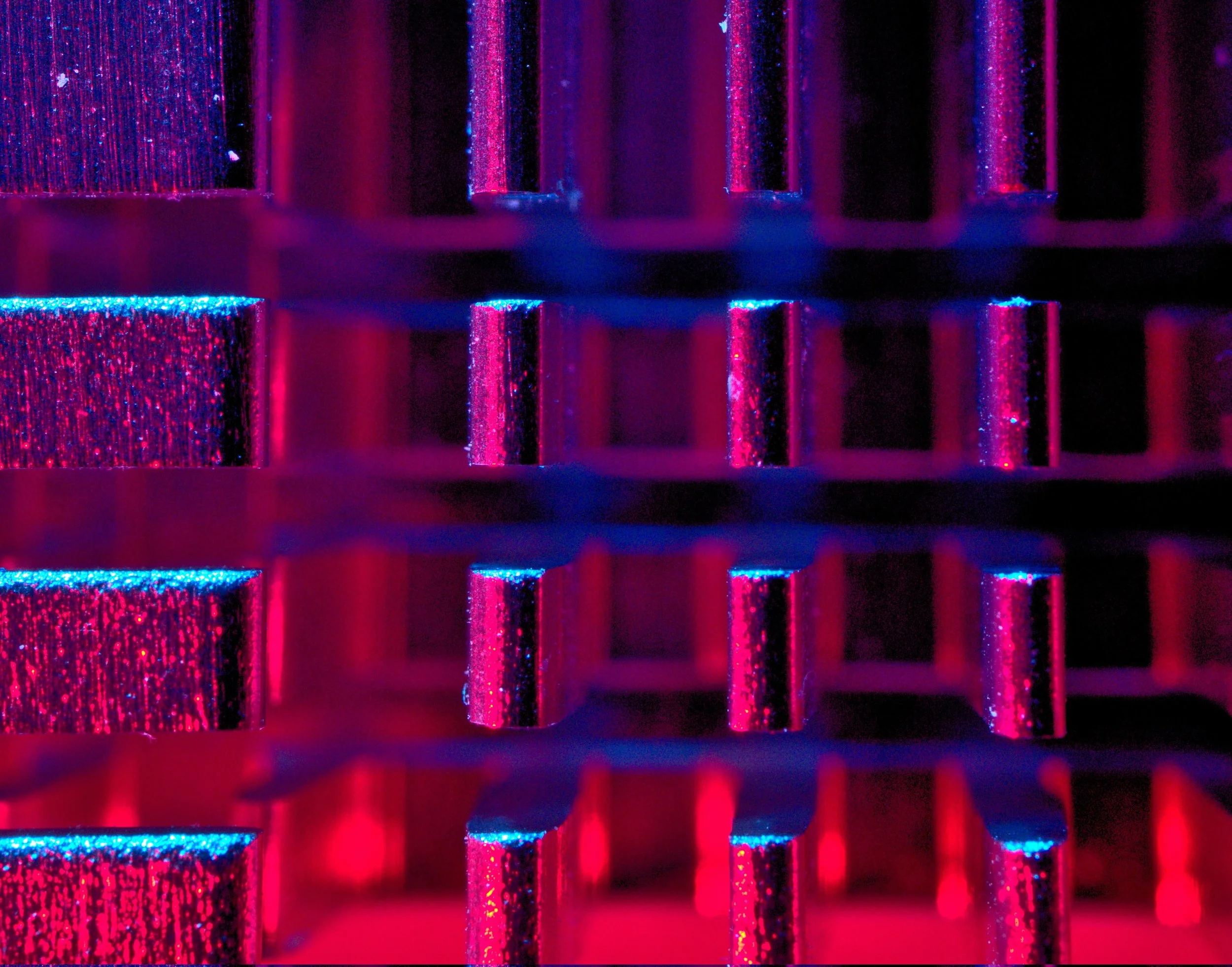 Close-up of a metallic heat sink with red and blue lighting, showing parallel fins and reflective surfaces.