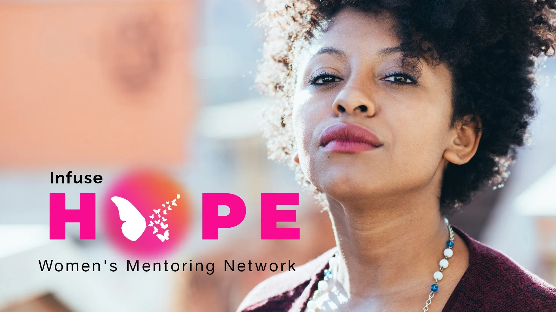 A woman looking at the camera with a glipse of hope, text: Infuse Hope, Women's Mentoring Network