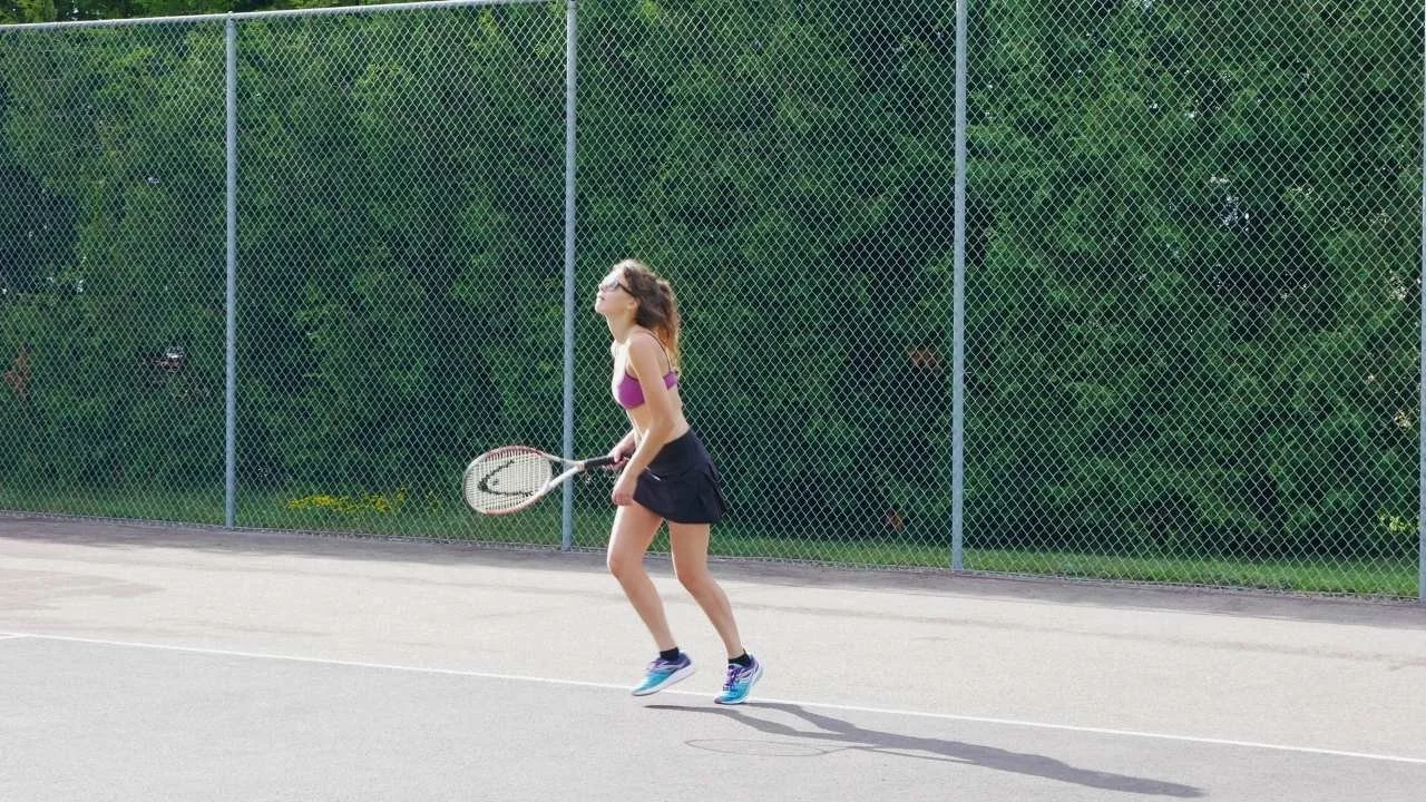 Holistic fitness coach Rozalia playing tennis with strength, agility, and mind‑body coordination during a powerful forehand swing.