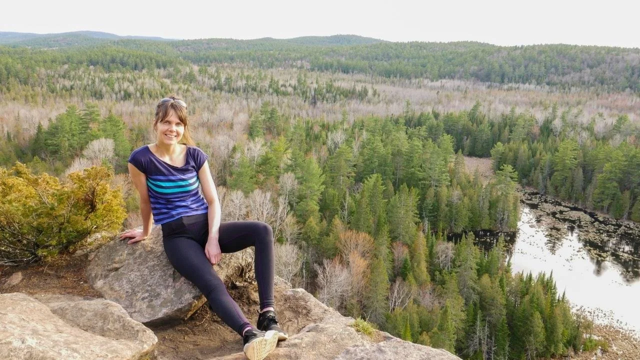 Travel wellness practitioner Rozalia sitting on a mountain, embracing stillness, presence, and natural energy alignment.