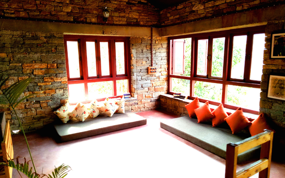 Bright stone lodge lounge with large windows, cushioned seating, and natural sunlight filling the space