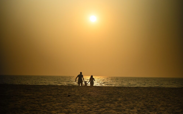 Silhouette of a family walking along a peaceful Sri Lankan beach at sunset, with golden skies, soft ocean waves, and tranquil coastal scenery capturing warmth, connection, and serenity.