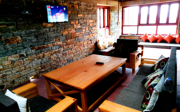 Rustic living room with wooden furniture, stone walls, and a television in a cozy lodge setting