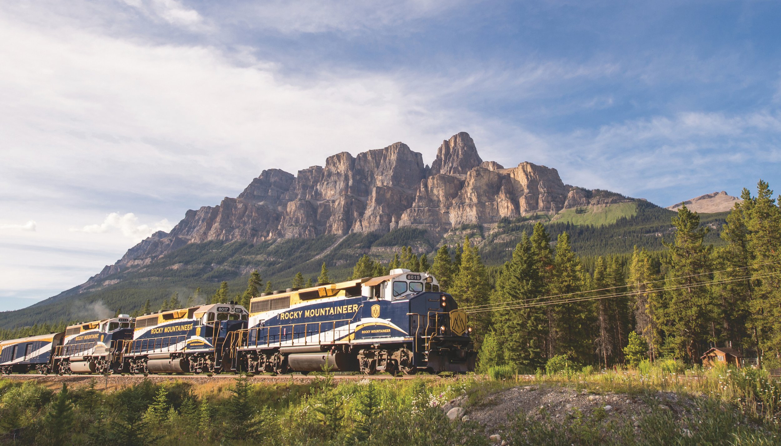 Rocky Mountaineer luxury train travelling through the Canadian Rockies with forested landscapes and mountain peaks