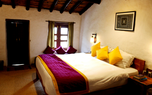 Warm rustic bedroom with wooden furniture, soft lighting, and colorful cushions in a mountain retreat