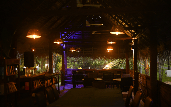 Cozy open-air library and lounge area at a Sri Lankan Ayurvedic retreat featuring warm lighting, wooden interiors, and relaxing communal spaces.