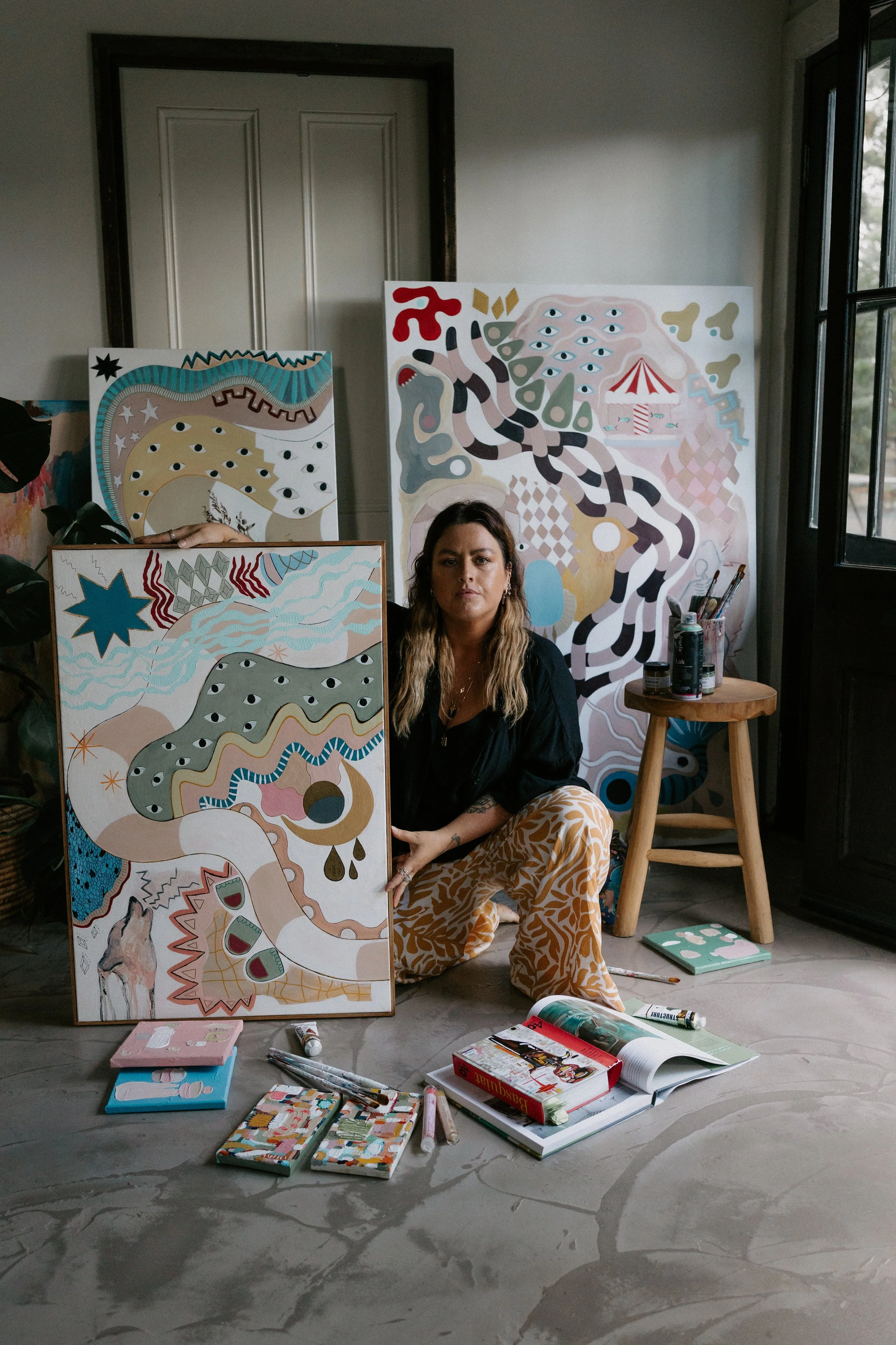 artsit keira wolf sits proudly with her paintings
