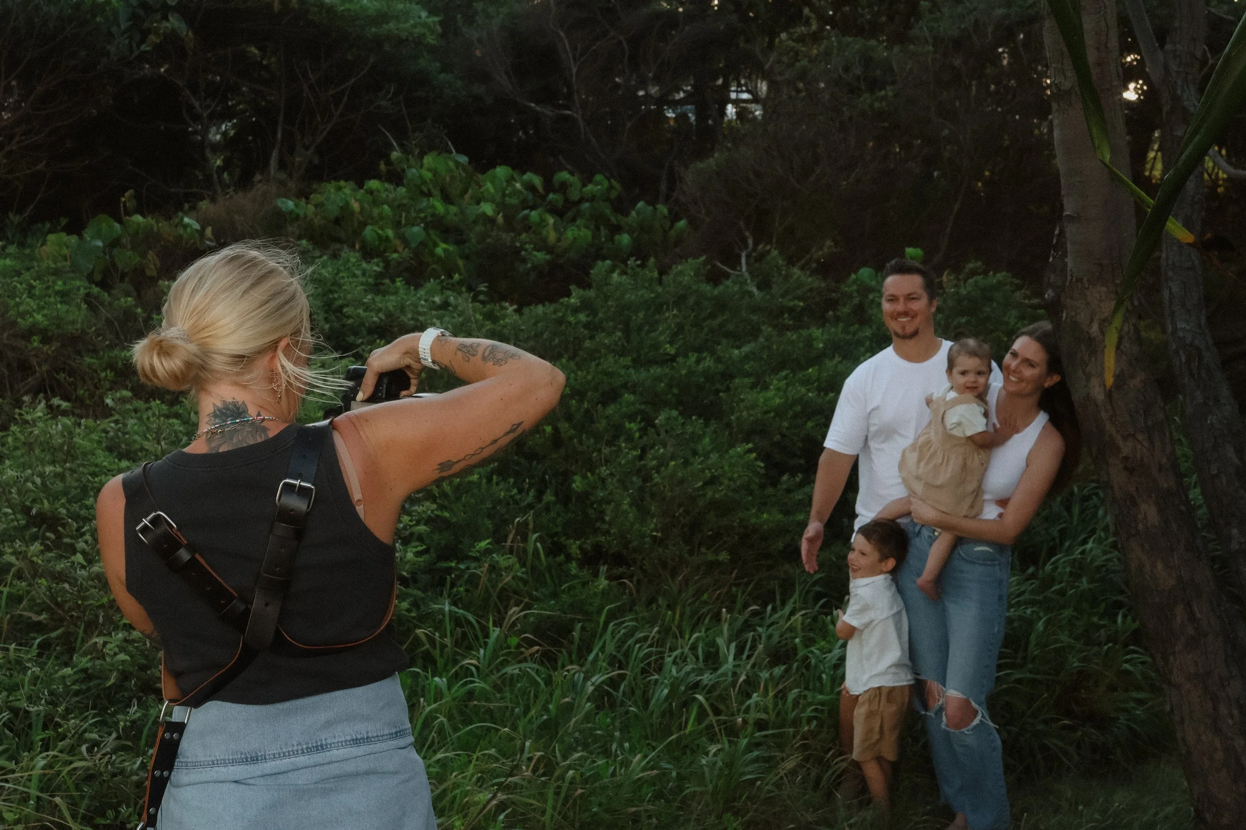 photographer takes a photo of a family under a tree