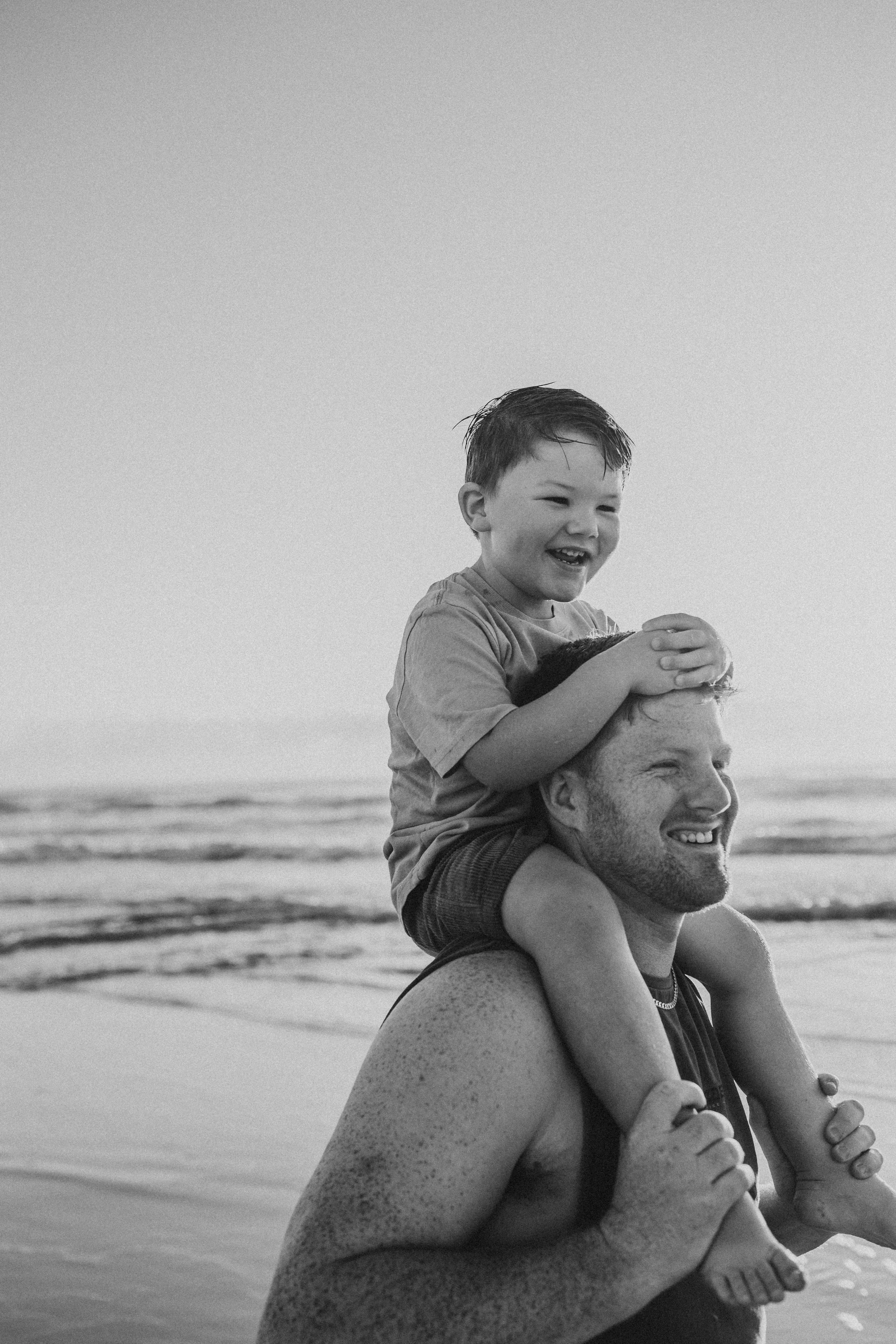 dad with son on shoulders on beach fun candid