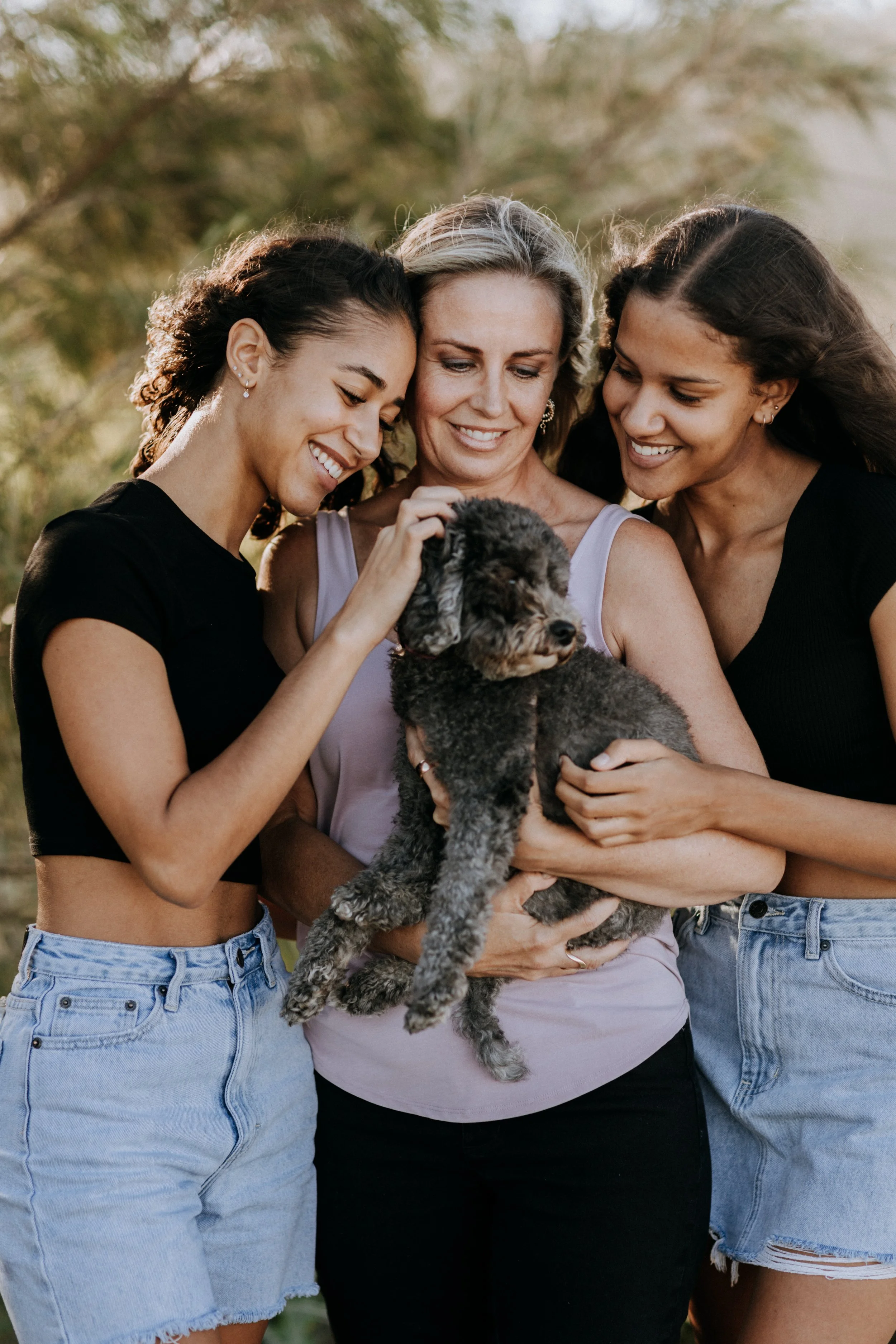 mum with teen daughters and pet dog cuddle