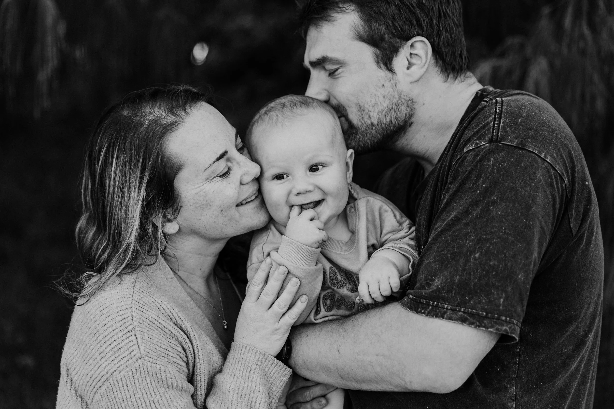 mum and dad kissing baby