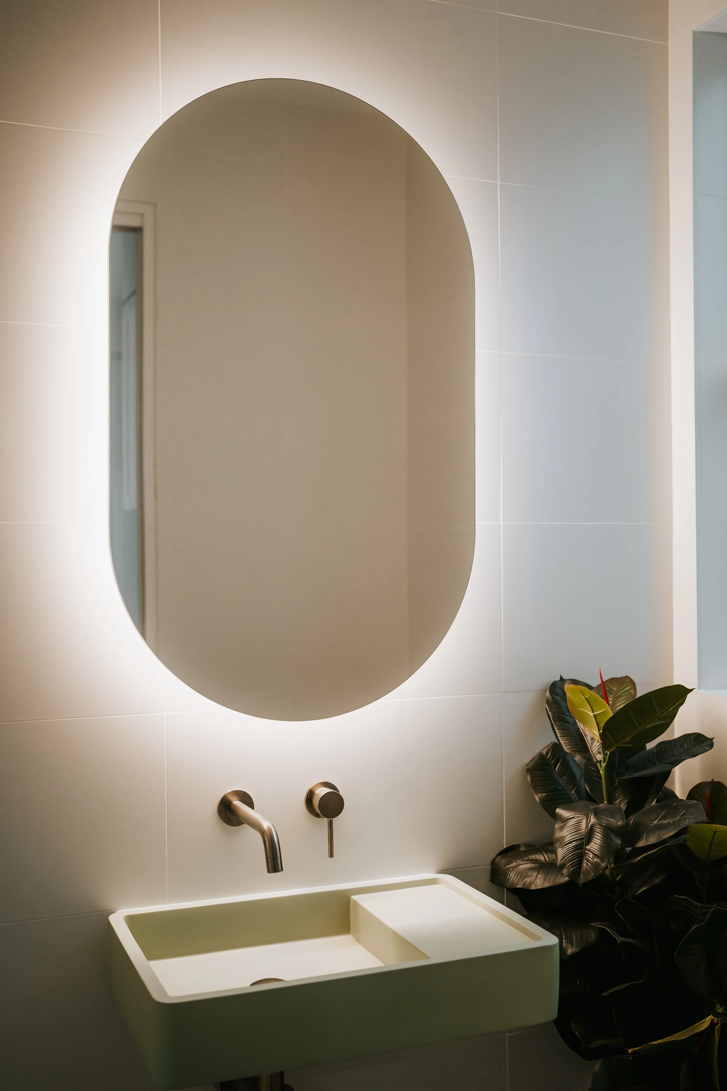 Modern powder room with curved mirror and ambient lighting in Cronulla home