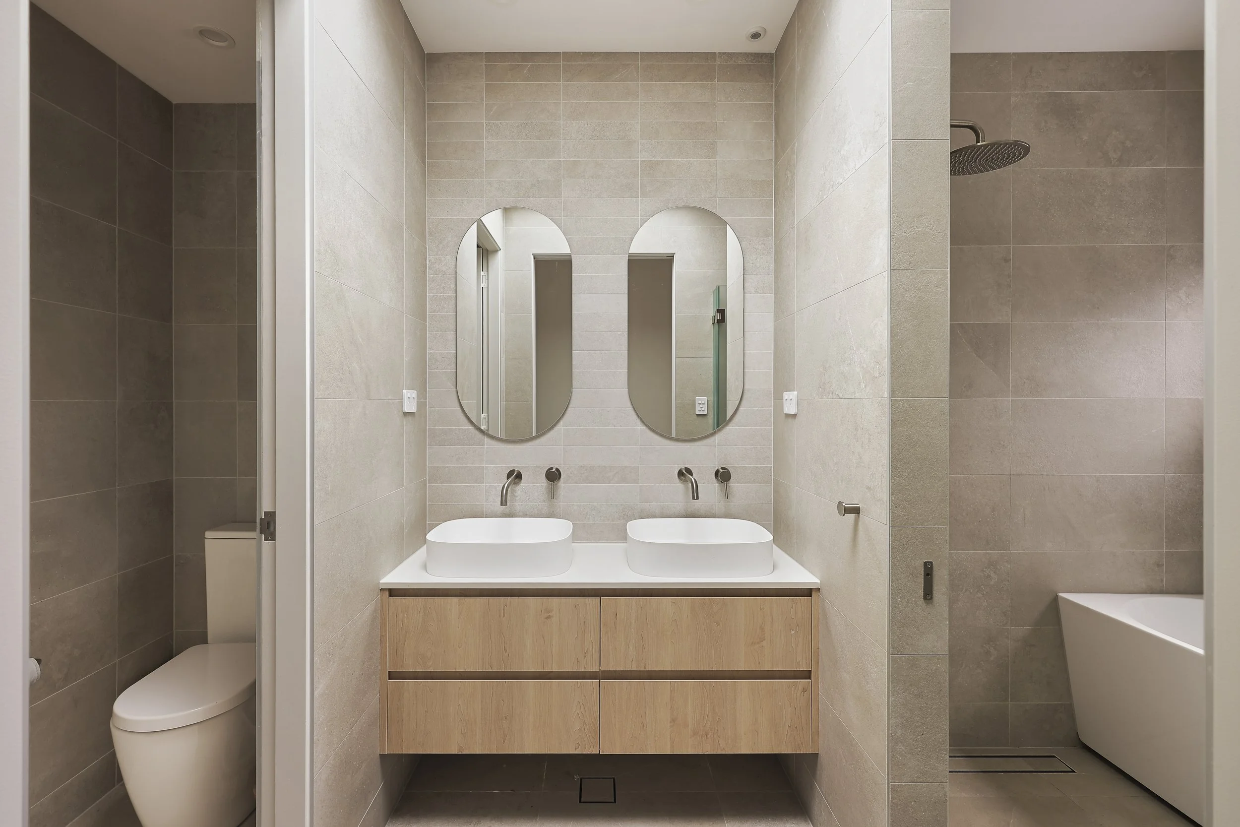 Modern bathroom with double vanity timber joinery and full height stone tiles