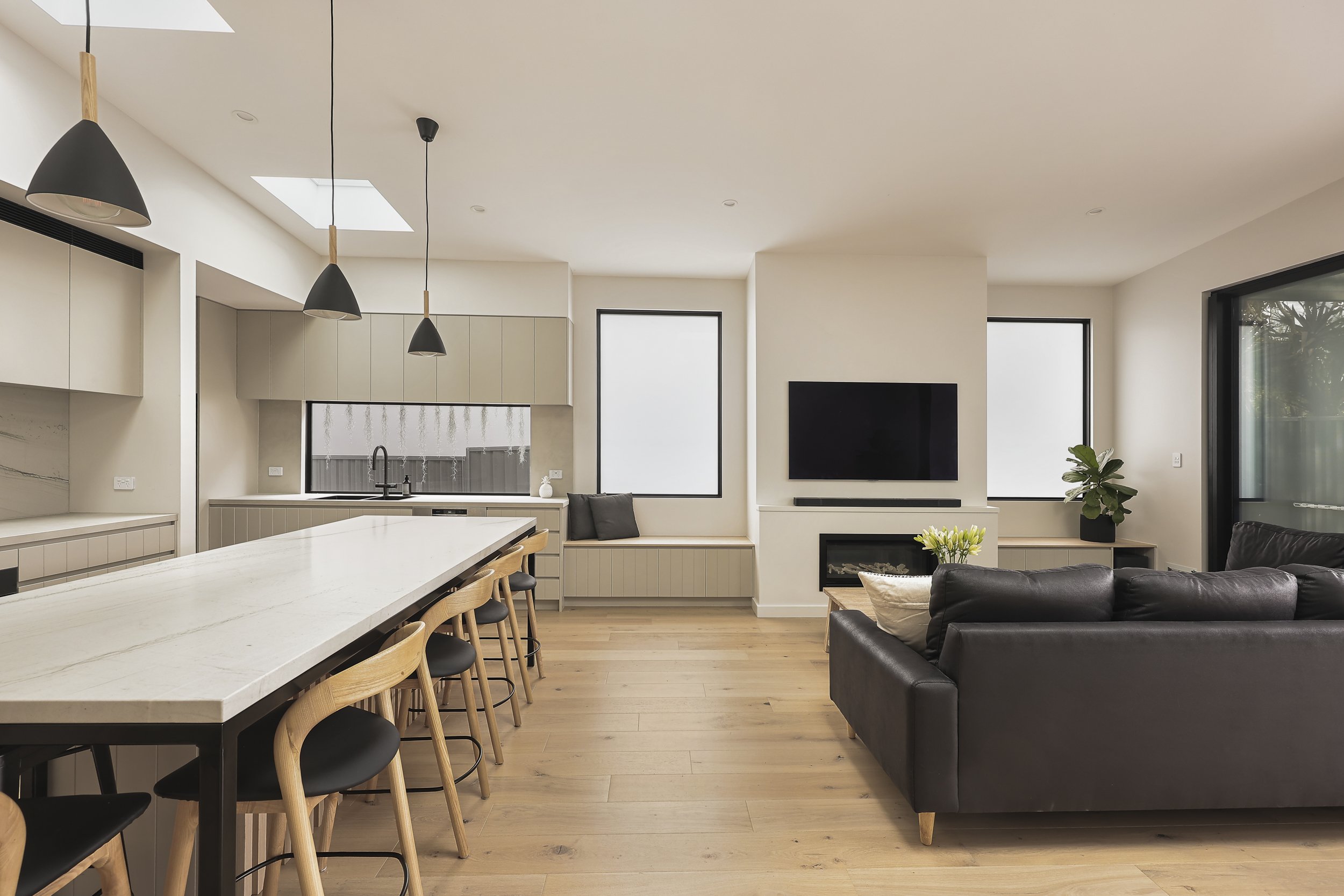 Open plan living and kitchen with skylights, stone island bench and timber flooring