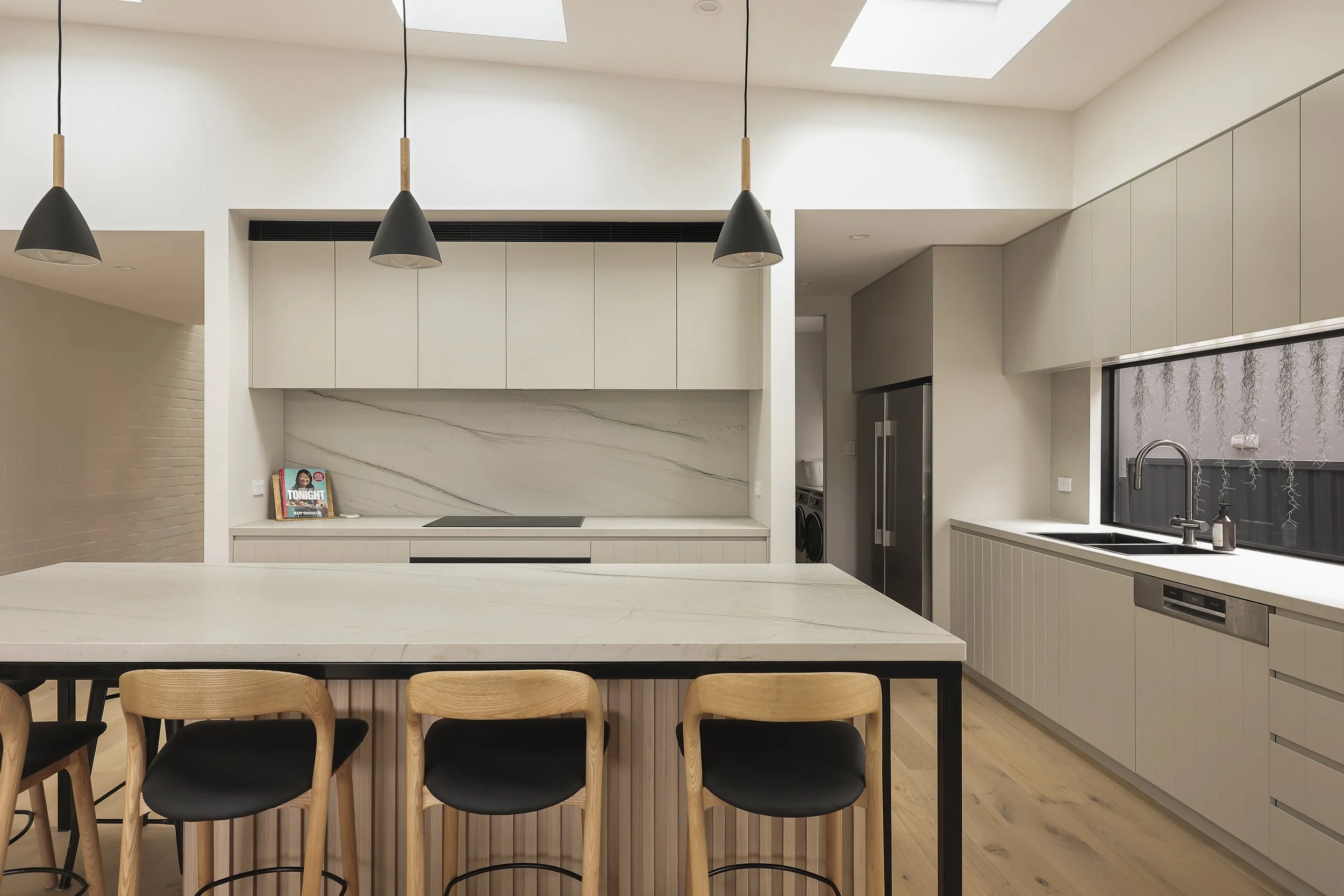 Custom kitchen with natural stone island, integrated cabinetry and skylights
