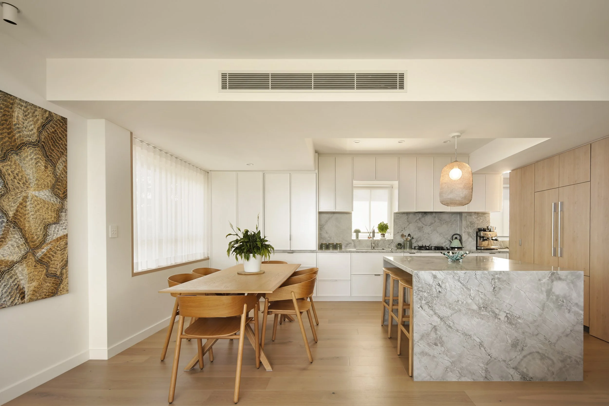 Dining area with timber table, custom cabinetry and stone kitchen benchtop