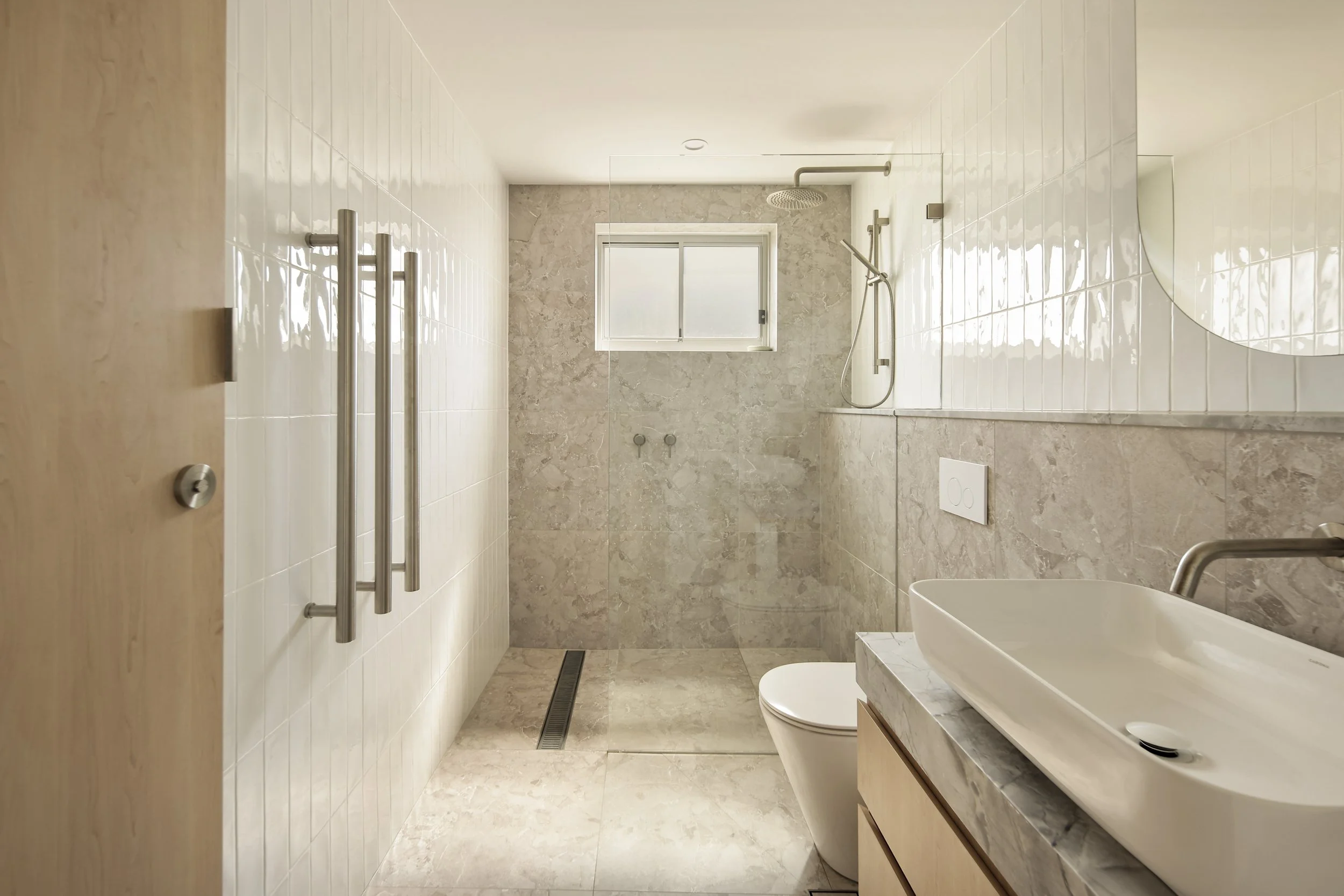 Bathroom with natural stone finishes, walk-in shower and custom vanity in luxury coastal home