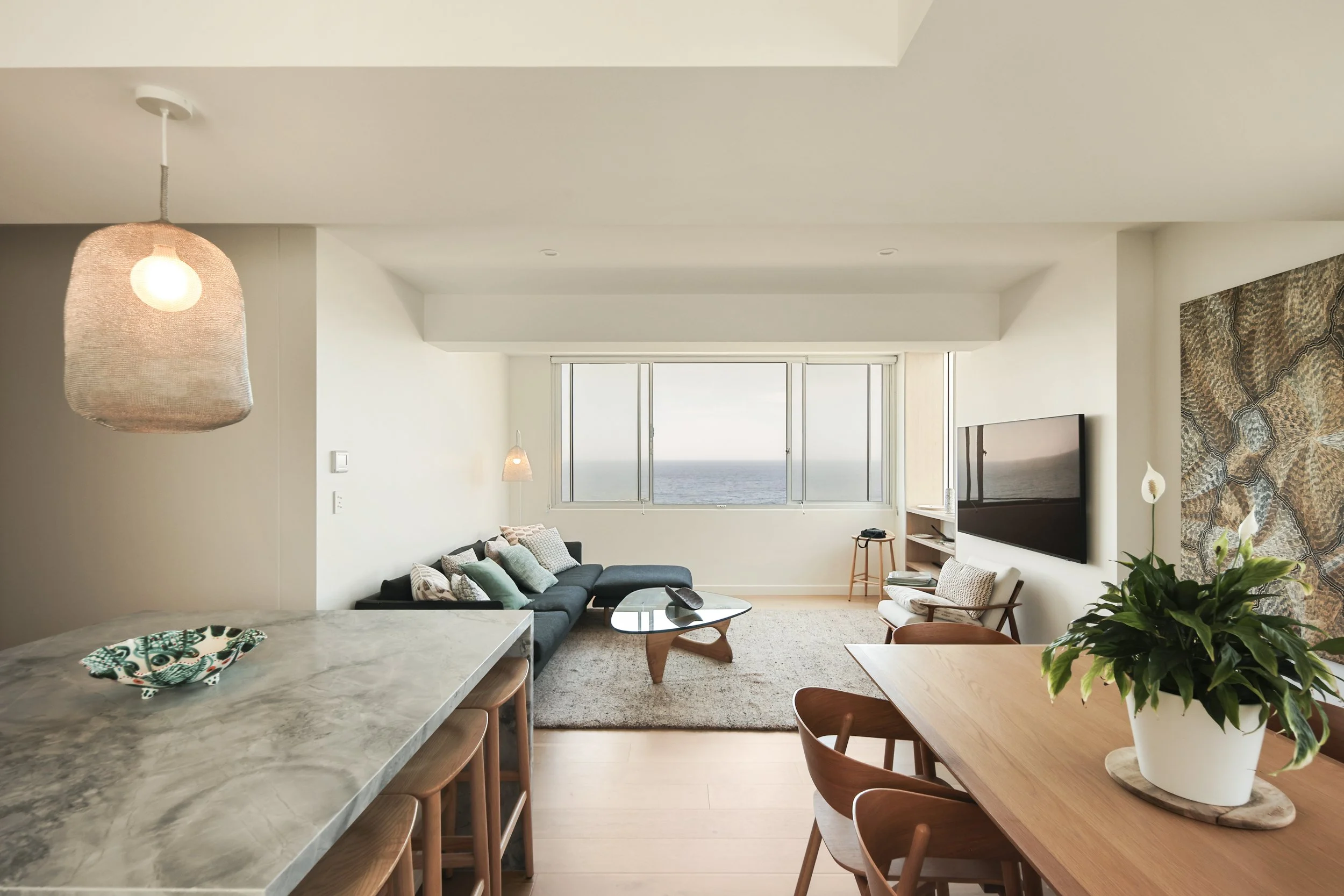 Kitchen with off-form stone island, timber cabinetry and integrated appliances