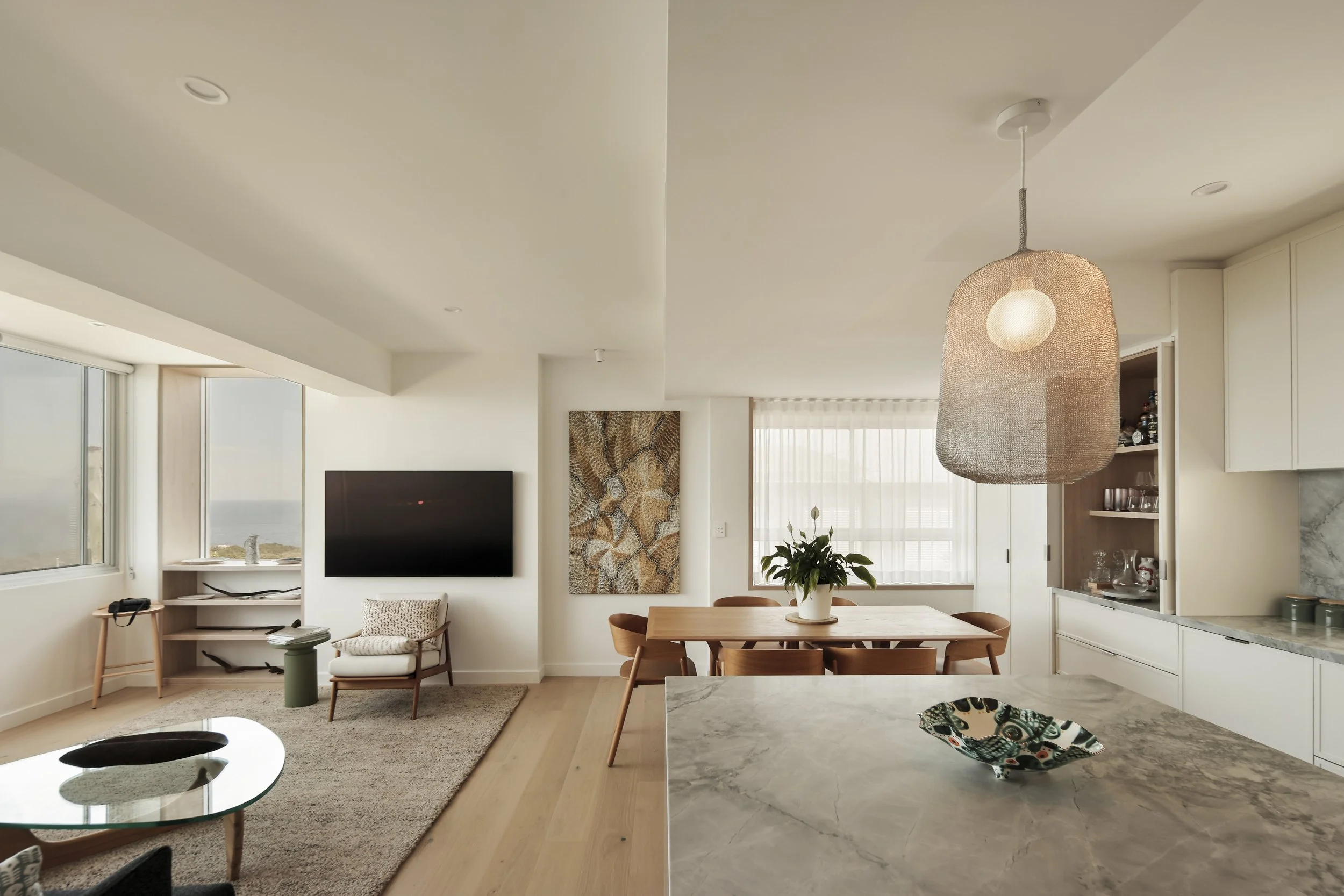 Open-plan living and dining area with marble island bench and custom joinery