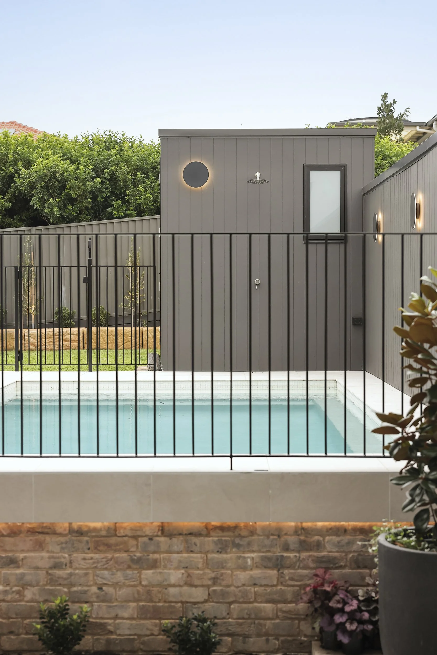 Swimming pool and outdoor shower building with modern cladding and architectural lighting