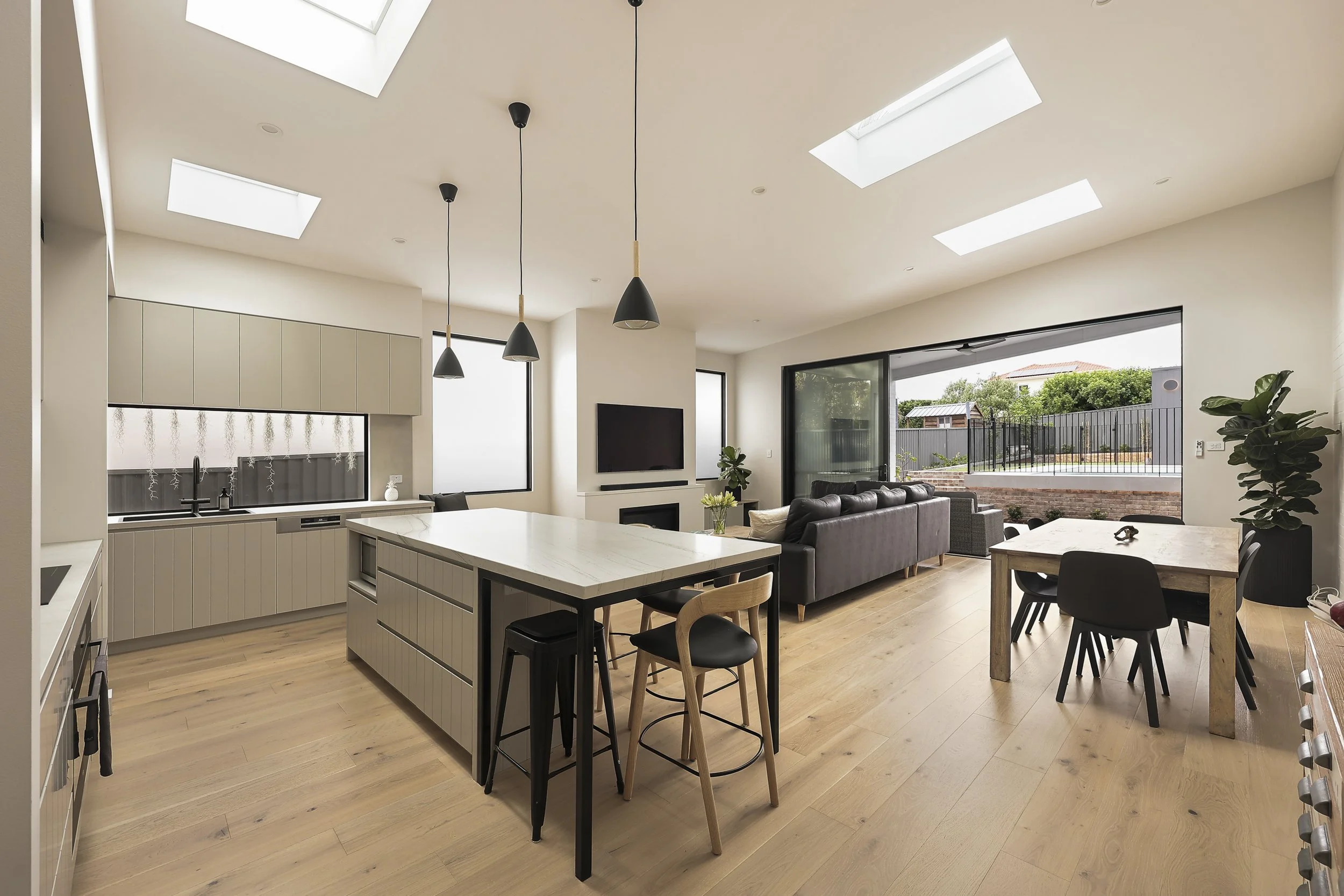 Open plan kitchen dining and living area with skylights and indoor outdoor connection
