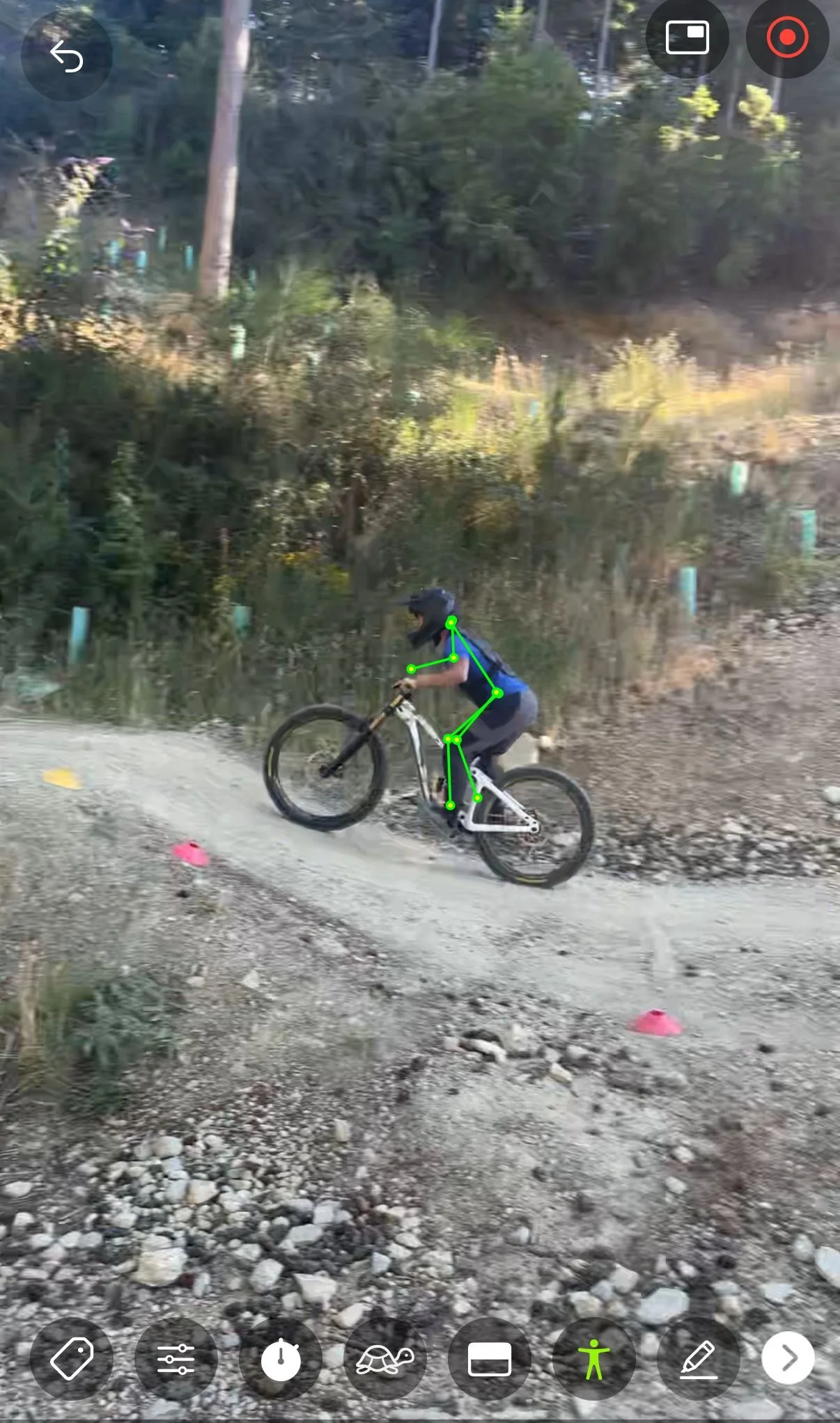 A person riding a mountain bike on a rugged trail surrounded by trees and bushes.