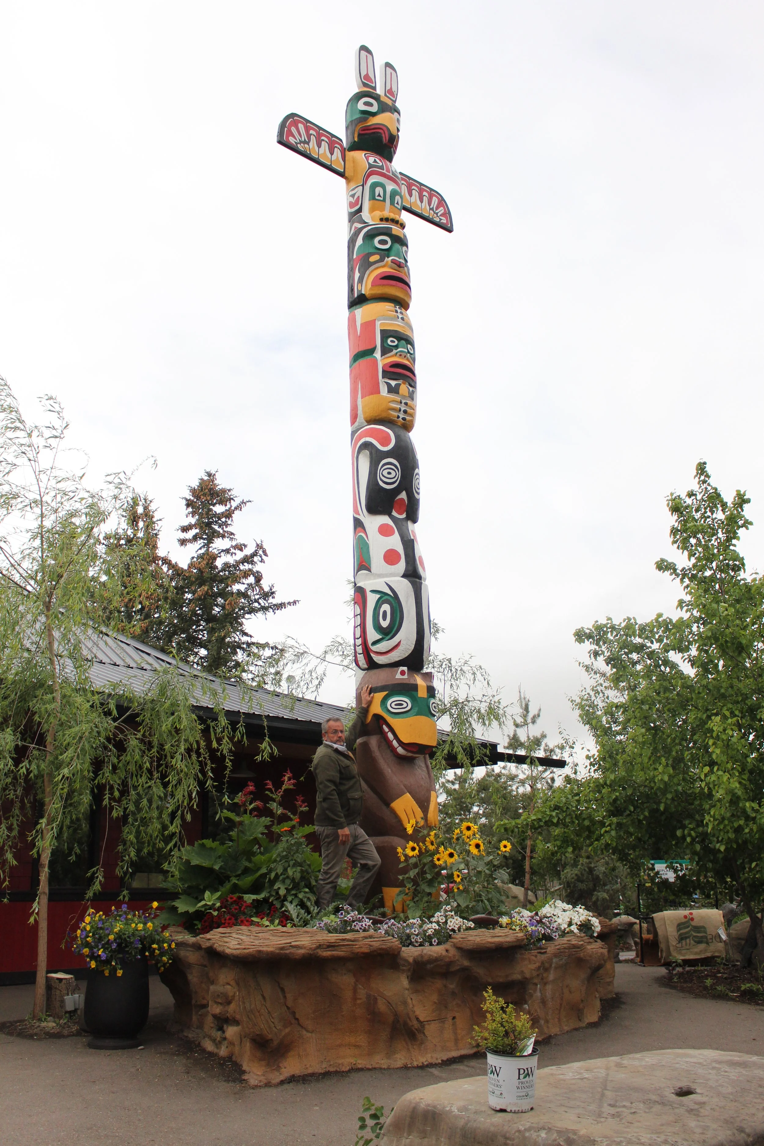 Colorful totem pole-style sign for Bell Hotel with advertising for family rates and air-conditioned rooms, set against a rural town background with old cars and historic grain elevators.