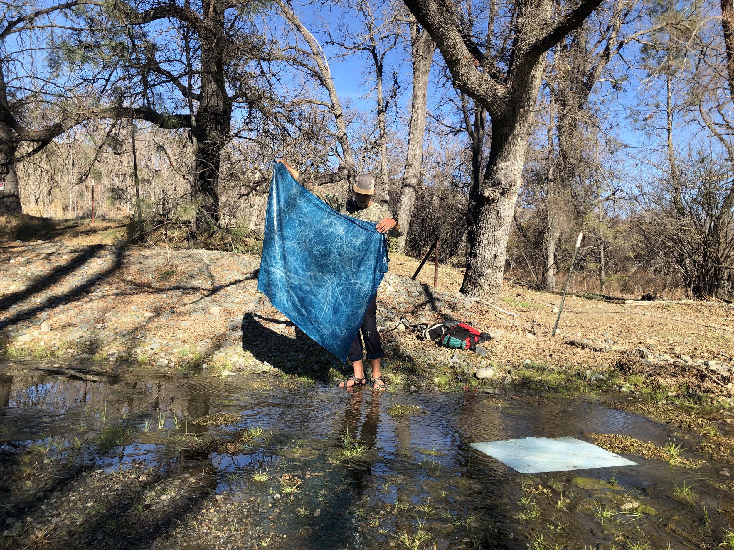 Processing and washing a cyanotype mural in a creek. 