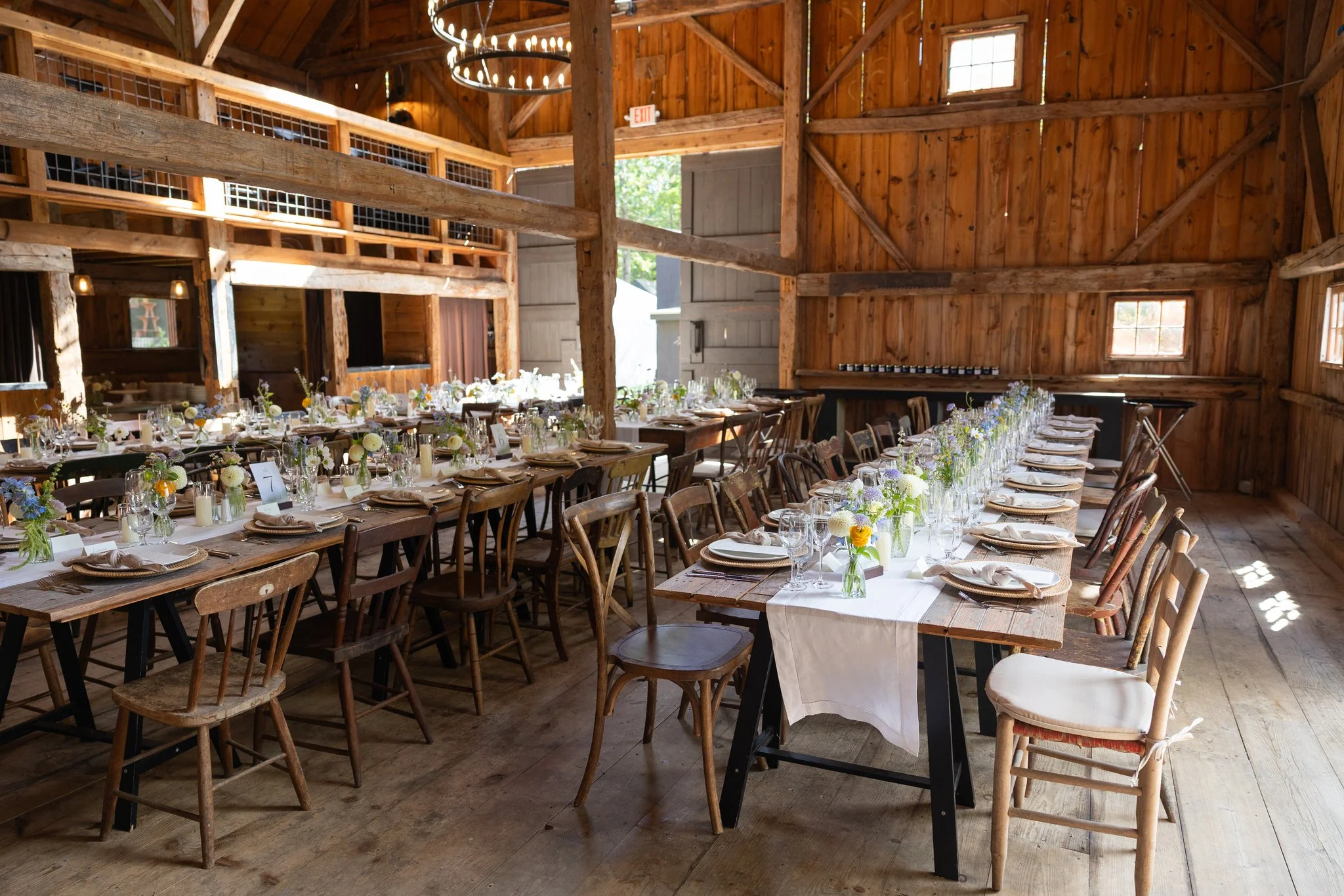 Interior of antique barn decorated with small flower bud vases by Celadon Floral at a Maine wedding