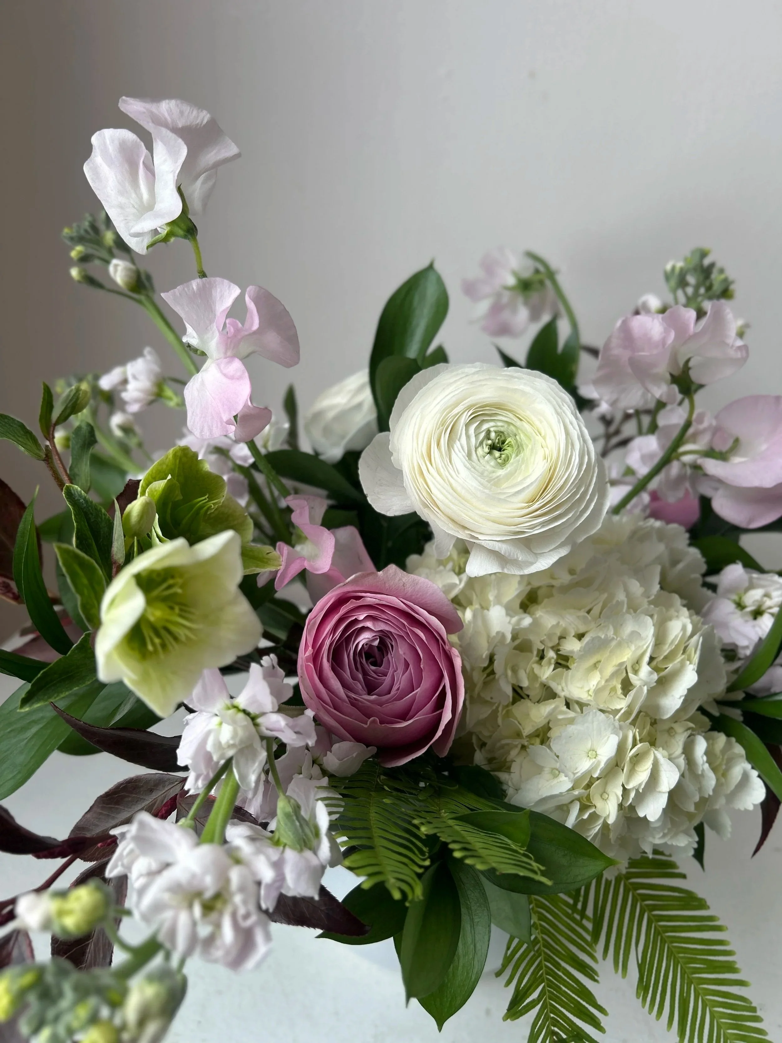 Stunning pastel flower arrangement with Garden Roses, Sweet Peas and Hellebore by Harpswell, Maine Florist