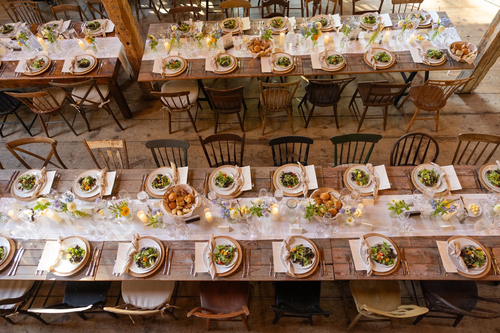 Aerial view of small bud vases filled with pale blue, lavender, white, and gold flowers arranged by Celadon Floral for a Maine wedding