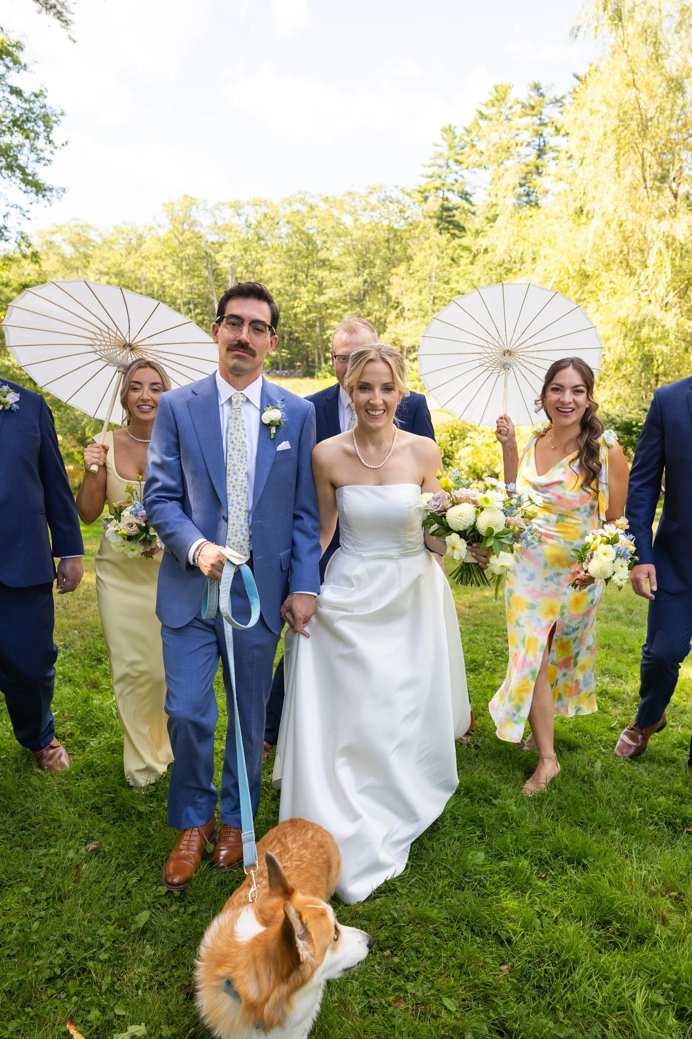 Maine Bride and Groom walking with their wedding party with pastel colored bouquets by Celadon Floral wearing colorful dresses and holding parasols.
