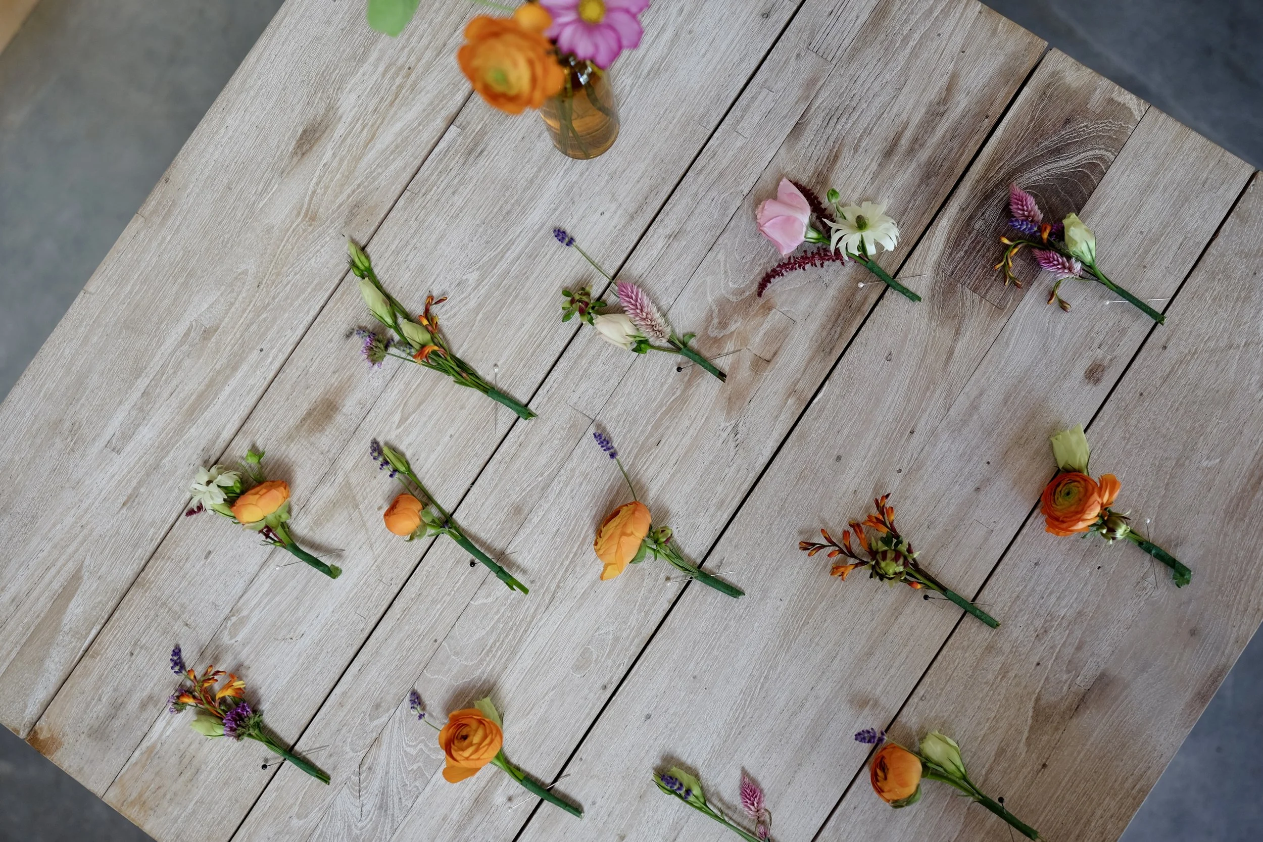 Several small bouquets of colorful flowers arranged on a wooden table.