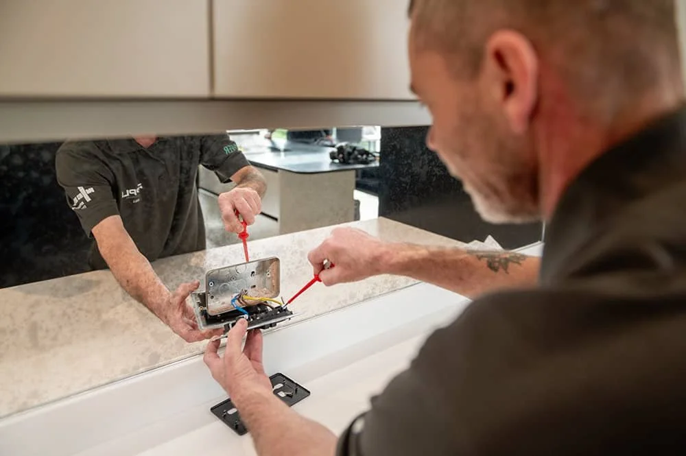 Electrical engineer installing a plug socket on a wall of company Ripple Electrical in Sevenoaks Kent