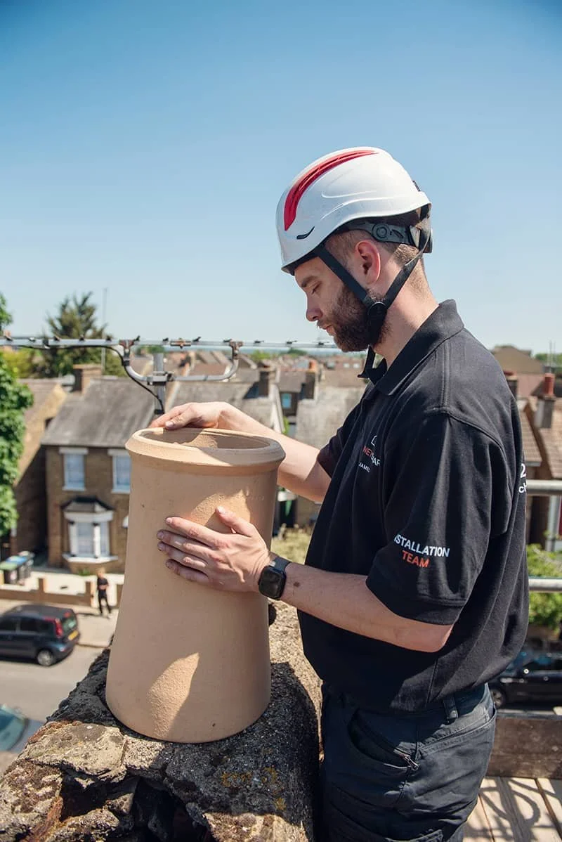 Chimney Installation team member on rooftop with chimney stack from company ChimneySmart in North London