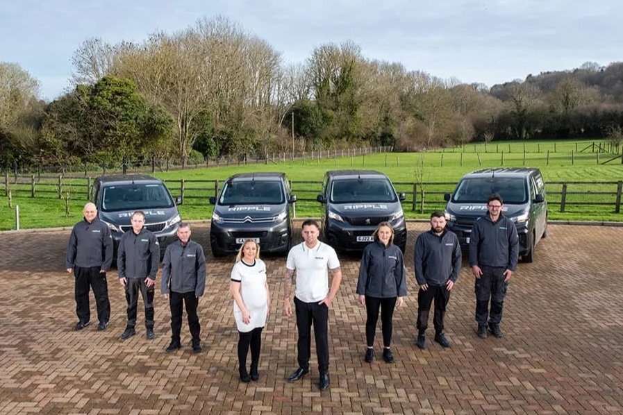 Two directors and six engineers of Ripple Electrical company standing in front of four branded van in Sevenoaks, Kent