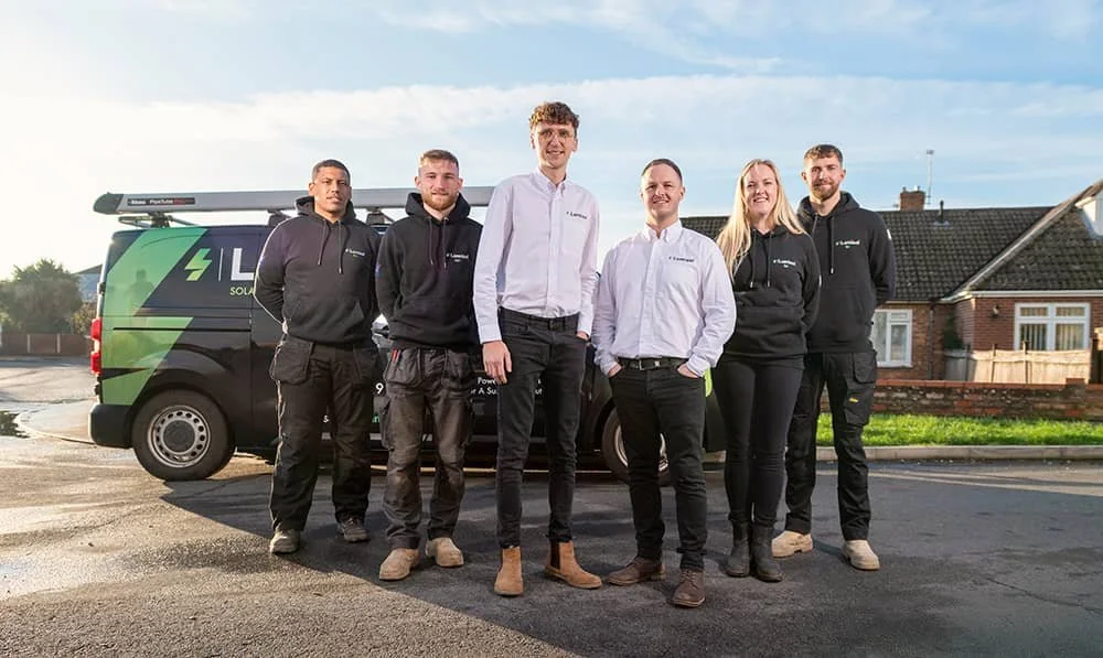 Two directors and four engineers of Lumisol electrical company standing in front of branded van in Norwich
