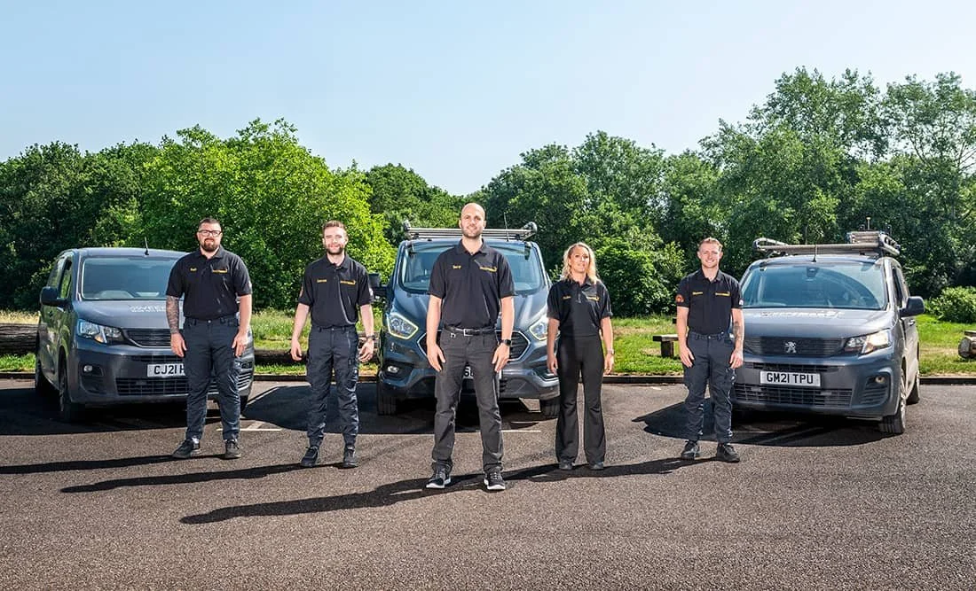 One director and four chimney sweeps of SweepSmart company standing in front of three branded vans in North London