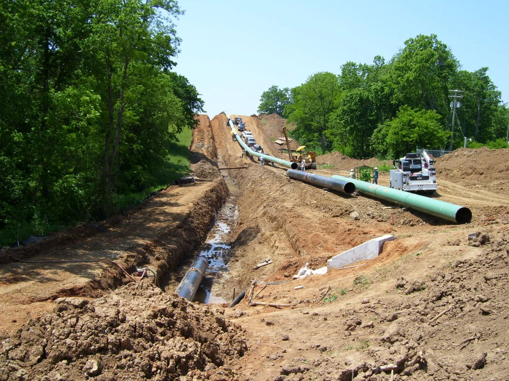 R.L. Coolsaet team stringing large-diameter pipeline across construction site in rural area
