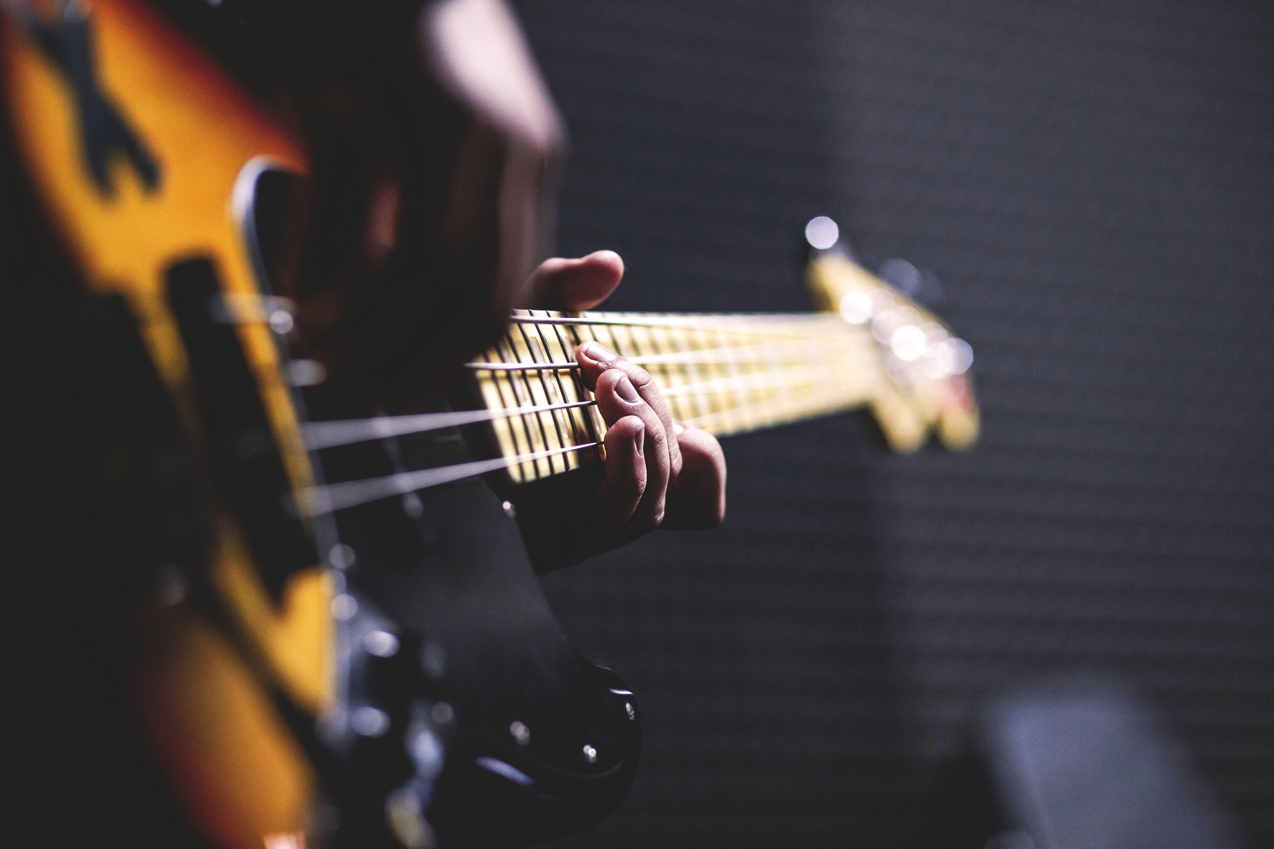 A person playing an electric guitar, close-up shot of their fingers on the fretboard.