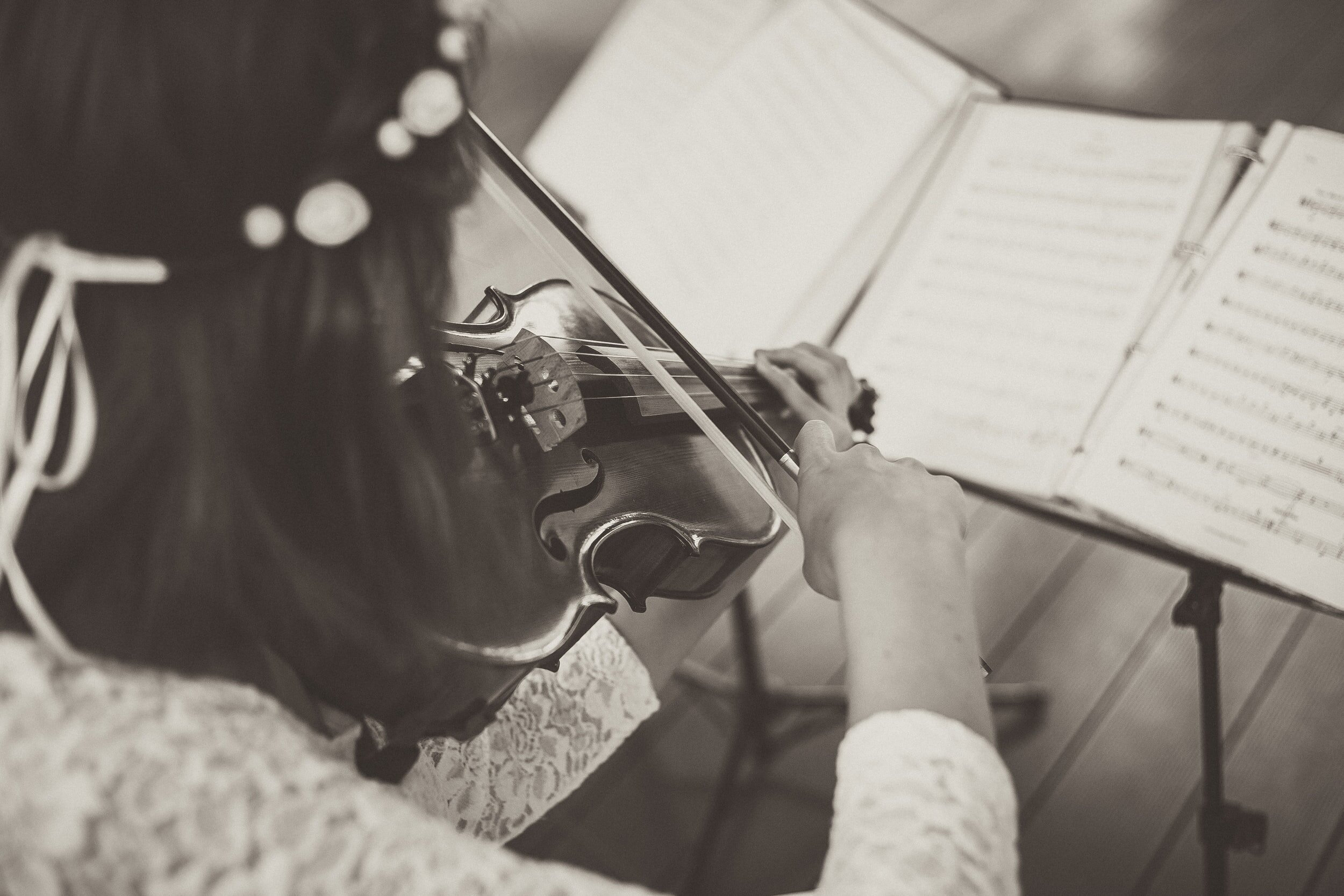 A person playing a violin with sheet music open in front of them.
