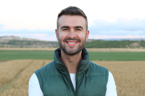 Smiling man with beard in front of farm field
