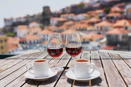 Red wine glasses next to full espresso cups in Italy