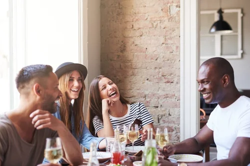 a group of friends laugh and drink wine