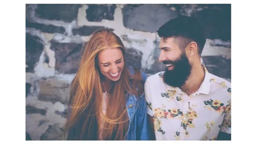 Laughing couple standing in front of a stone wall