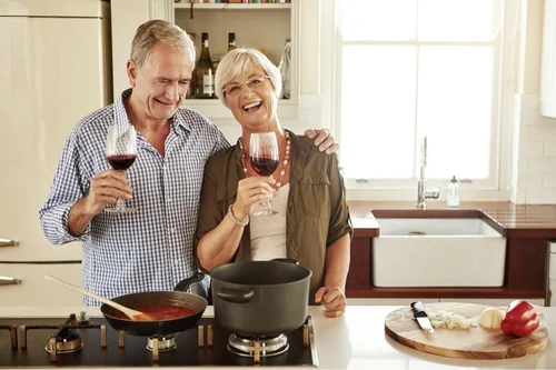 Cooking with Wine Older Smiling Couple in Kitchen with Red Winejpg