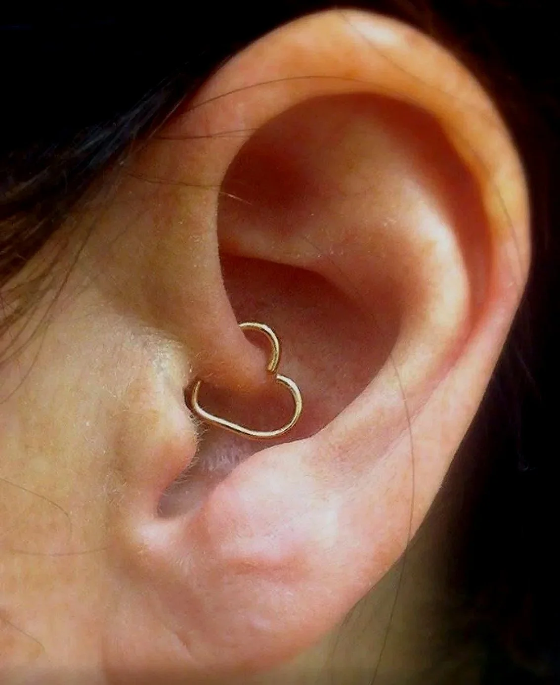 Close-up of a human ear with two small gold hoop earrings near the earlobe.